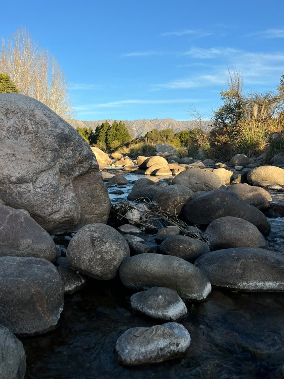 Piedras redondeadas en el cauce del rio con luz dorada